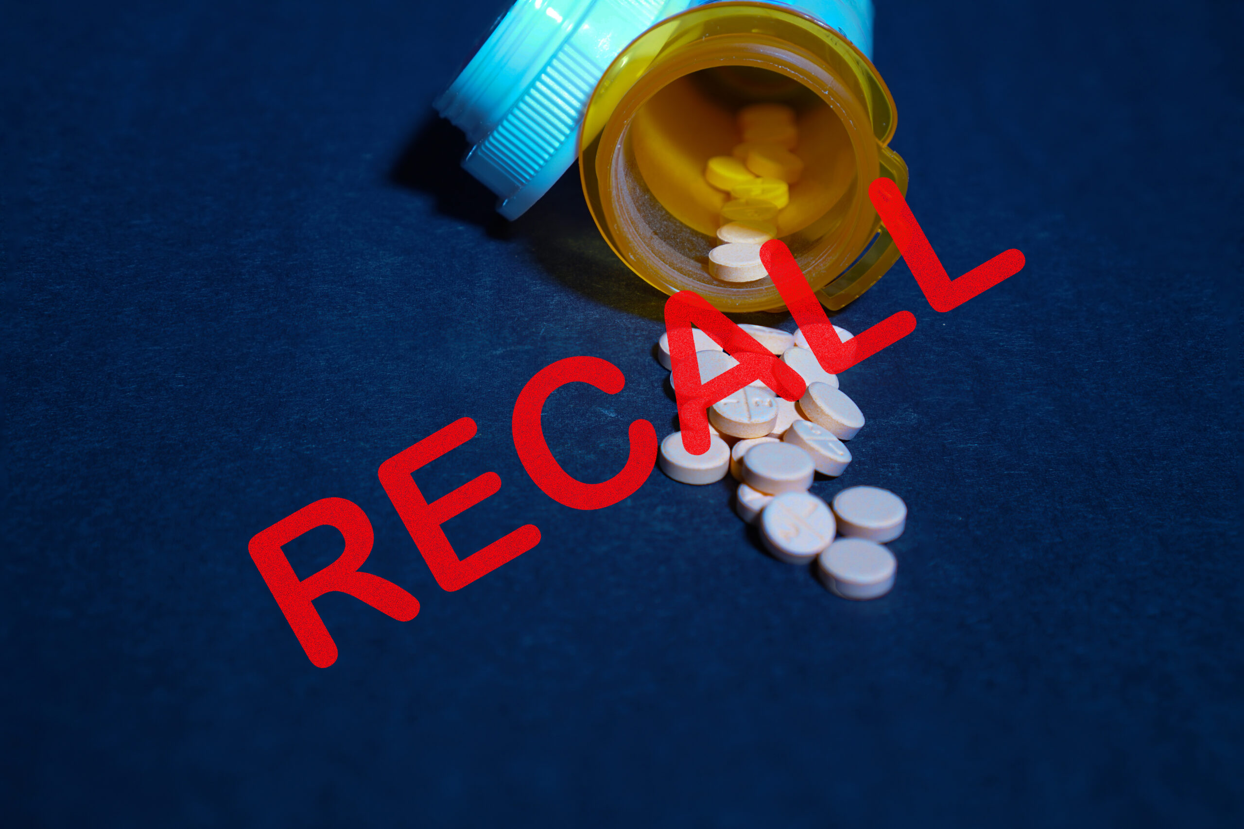 Pills spilling out of container with the word Recall written across