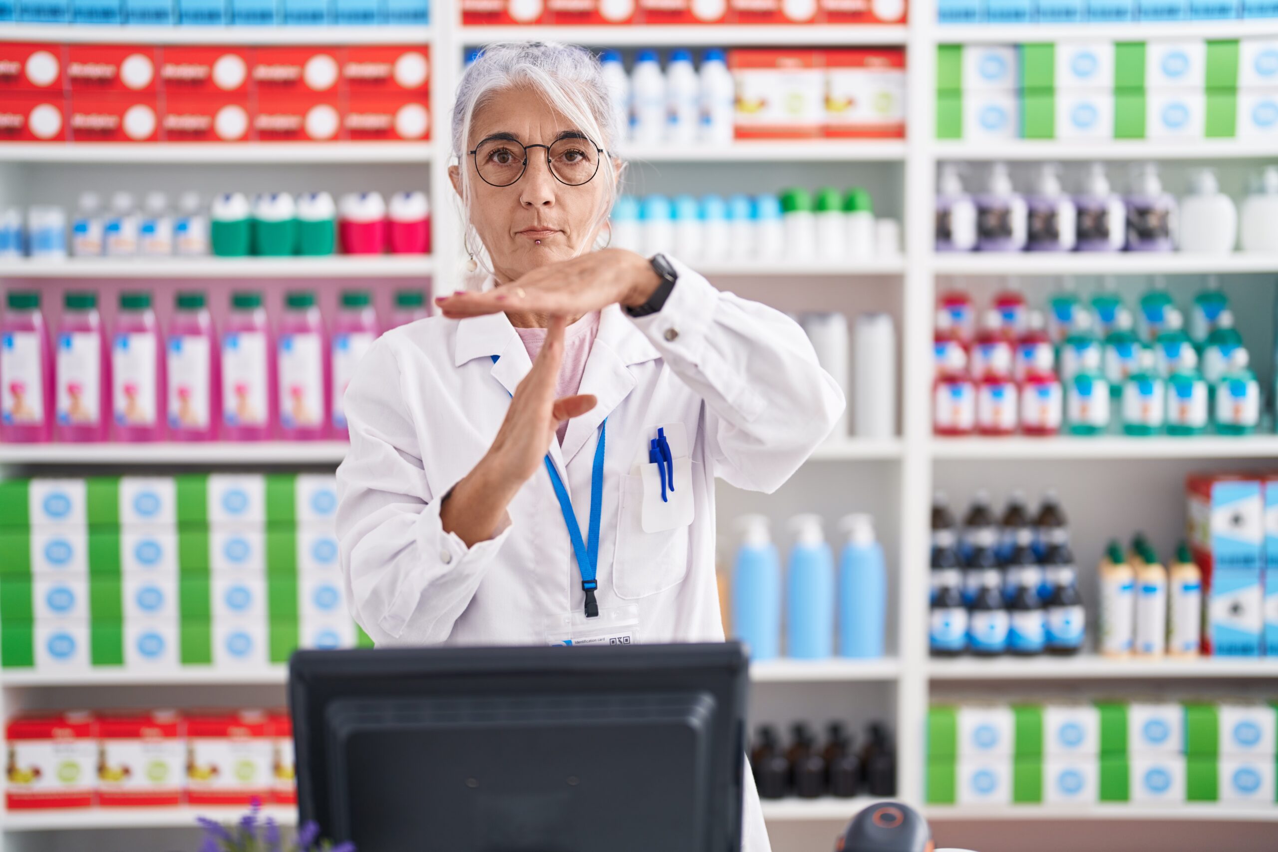 Female pharmacist holding her hands up making the time-out sign because she is frustrated with receiving so many checks for her expired products